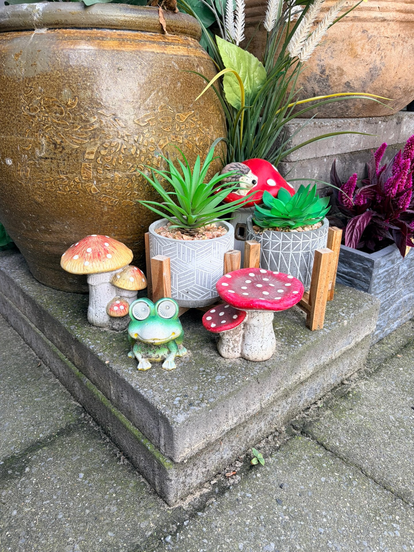 Keramische paddenstoelen en een kikker naast een grote pot