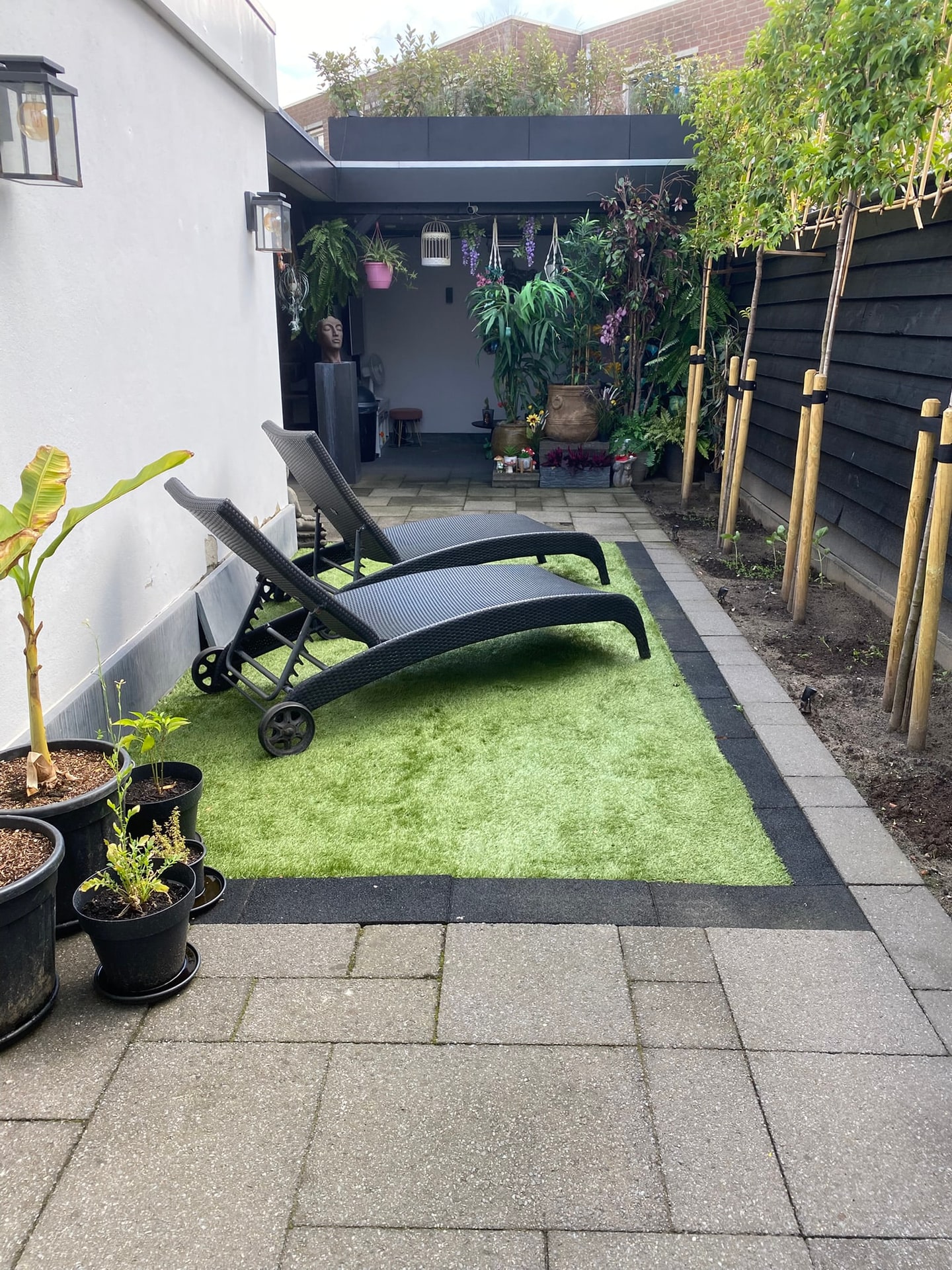 De tuin nu: het gras en de plantenbakken op de overkapping