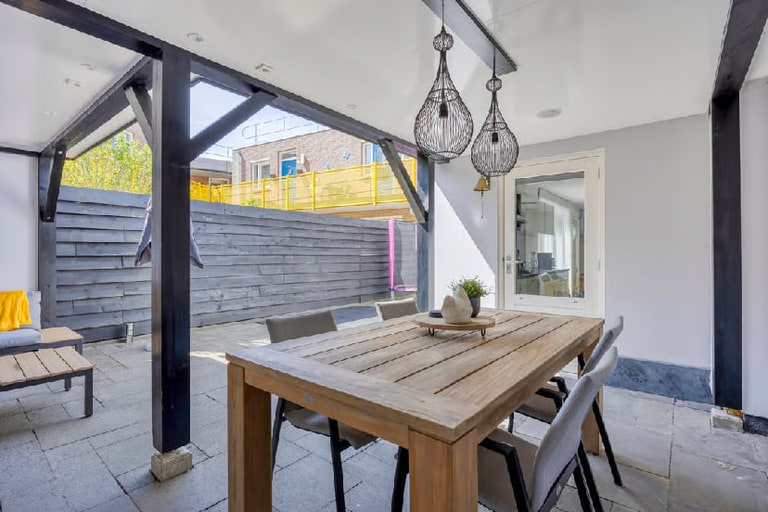 De tuin bij aankoop: overkapping met eettafel en veel bestrating