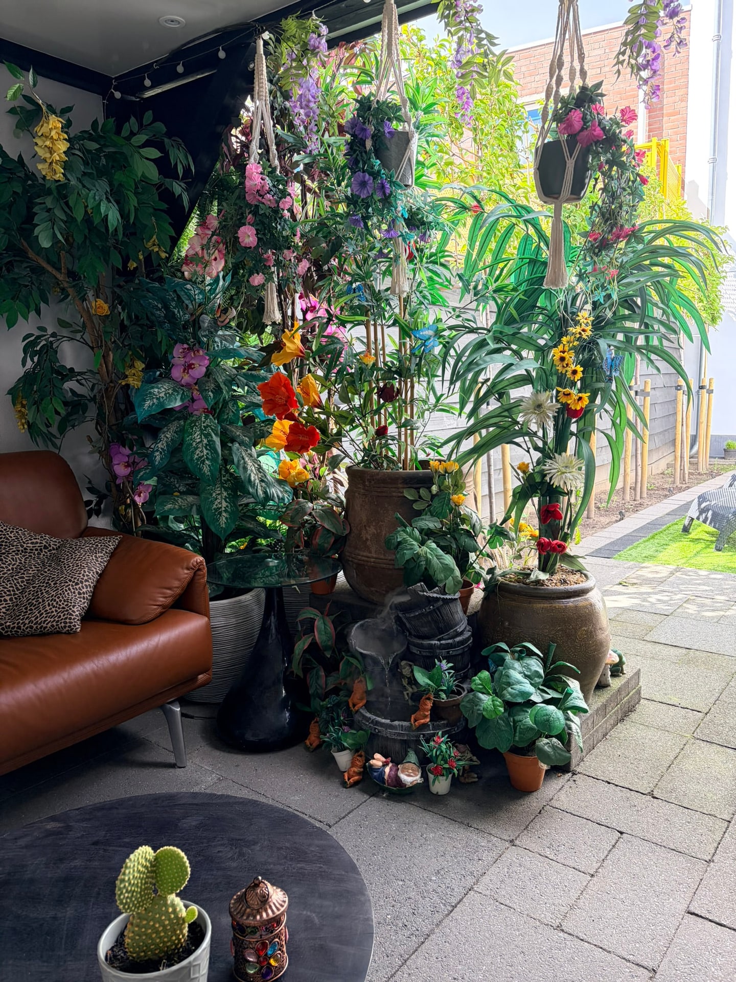 De wand van planten en bloemen naast de zithoek, met het mistende waterornament