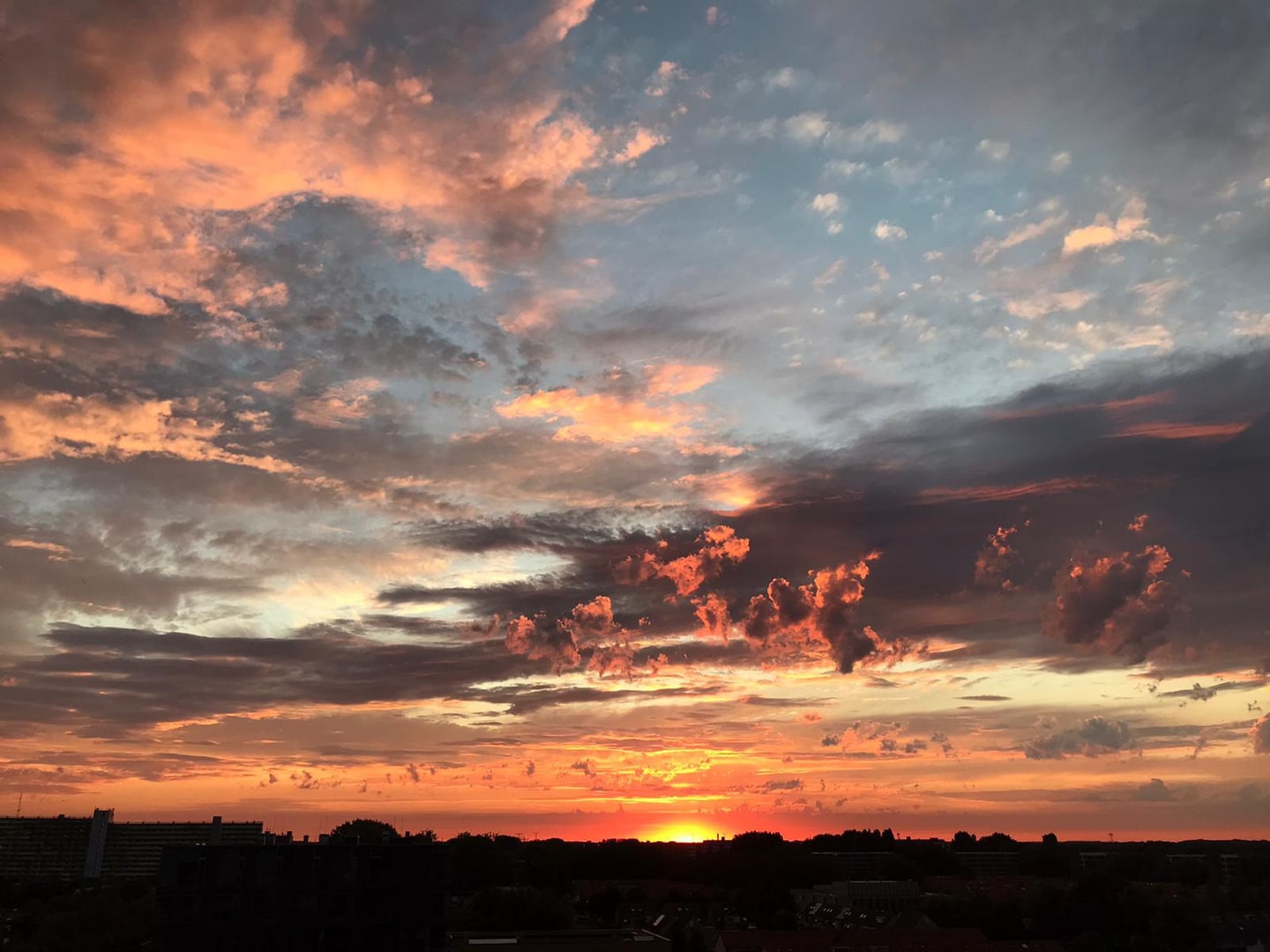 Een zonsondergang met oranje en paarse wolken boven donker land