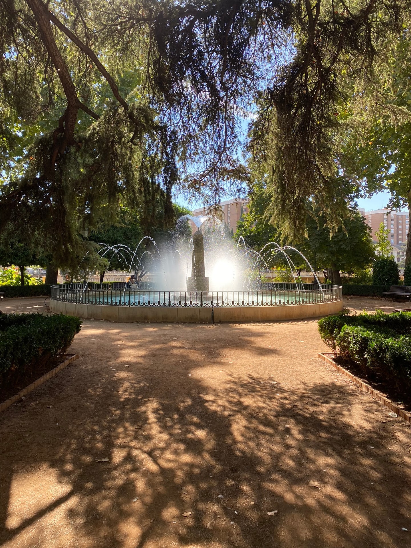 Een fontein in een stadspark, met bomen eromheen