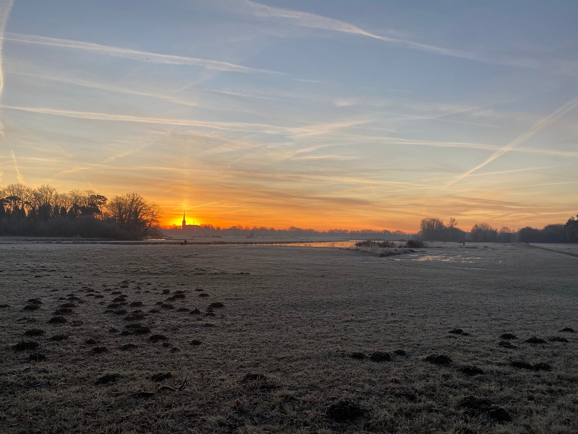 Zonsopkomst boven een bevroren akker, met strepen in de lucht