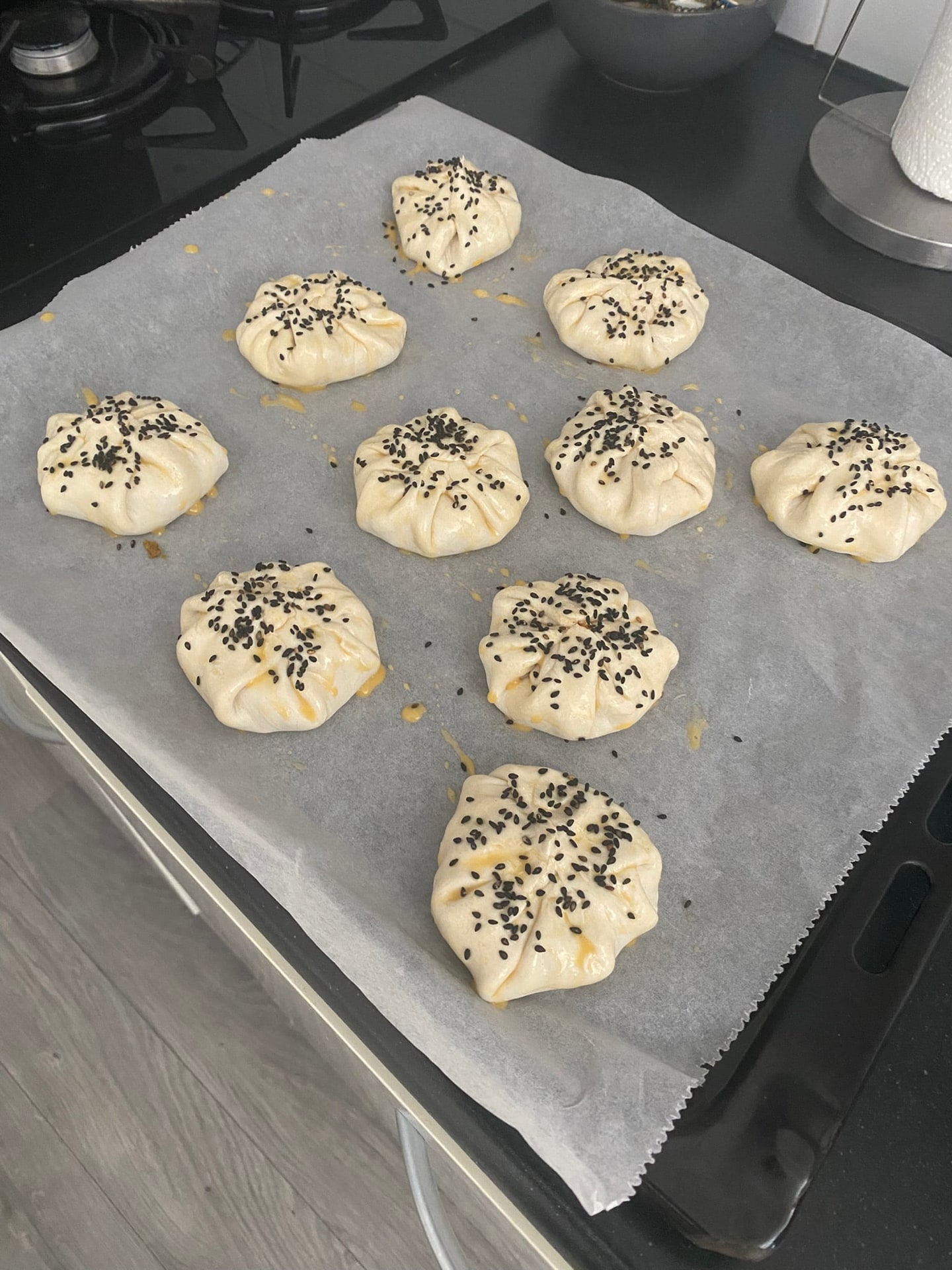 De balletjes dichtgevouwen op de bakplaat, bestrooid met zwarte sesam
