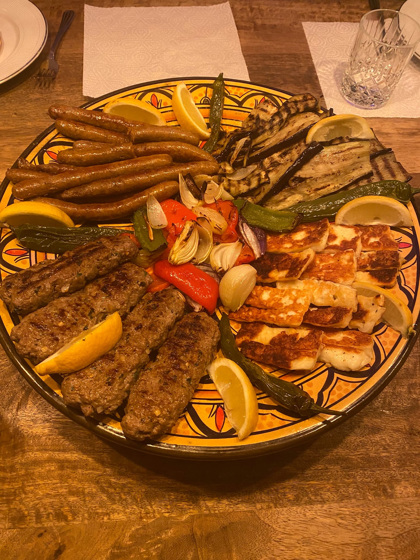 Een schaal met gegrild vlees, courgette, paprika en partjes citroen