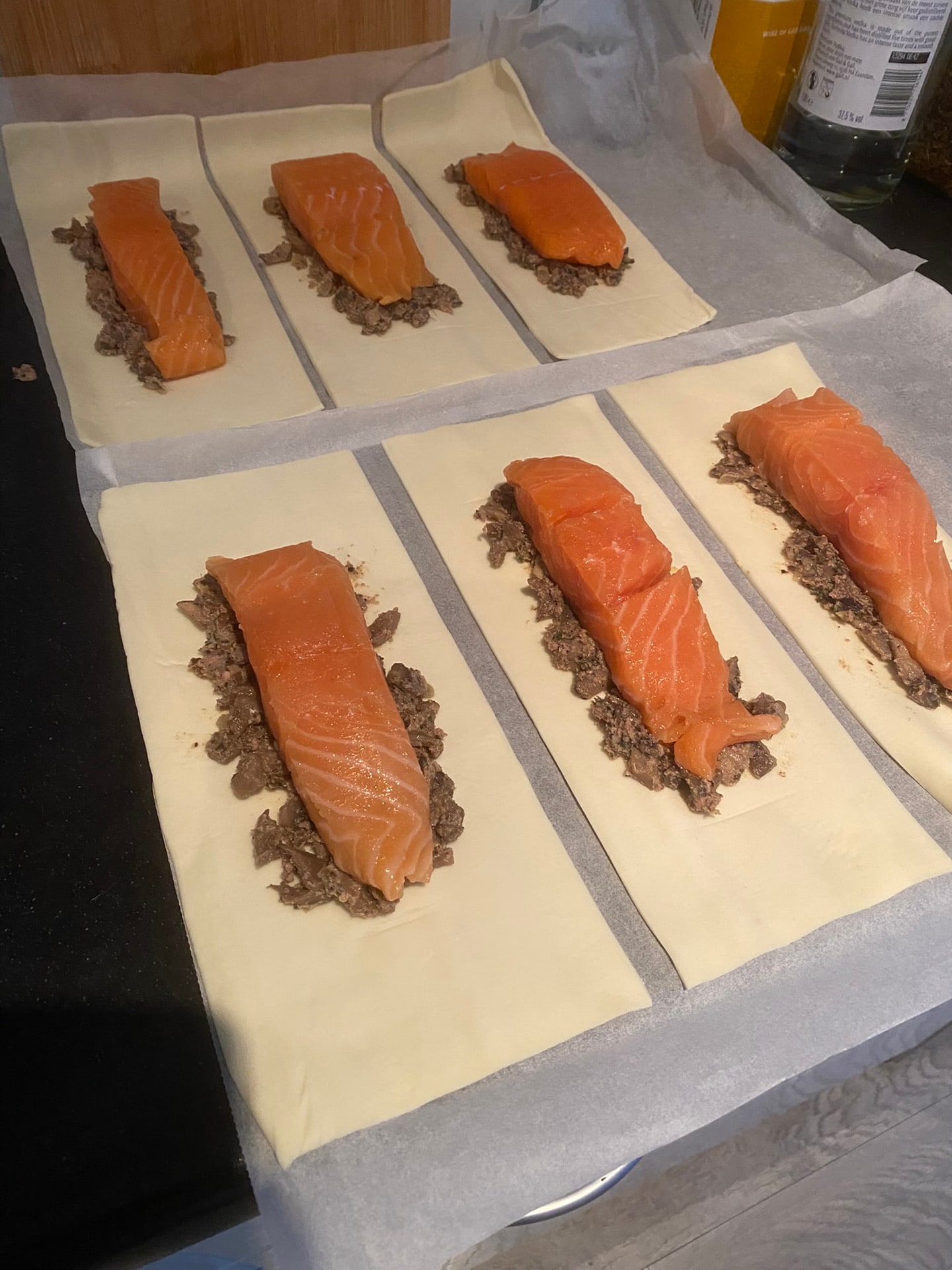 Zalmfilets op een laagje vulling, klaargelegd op vellen bladerdeeg