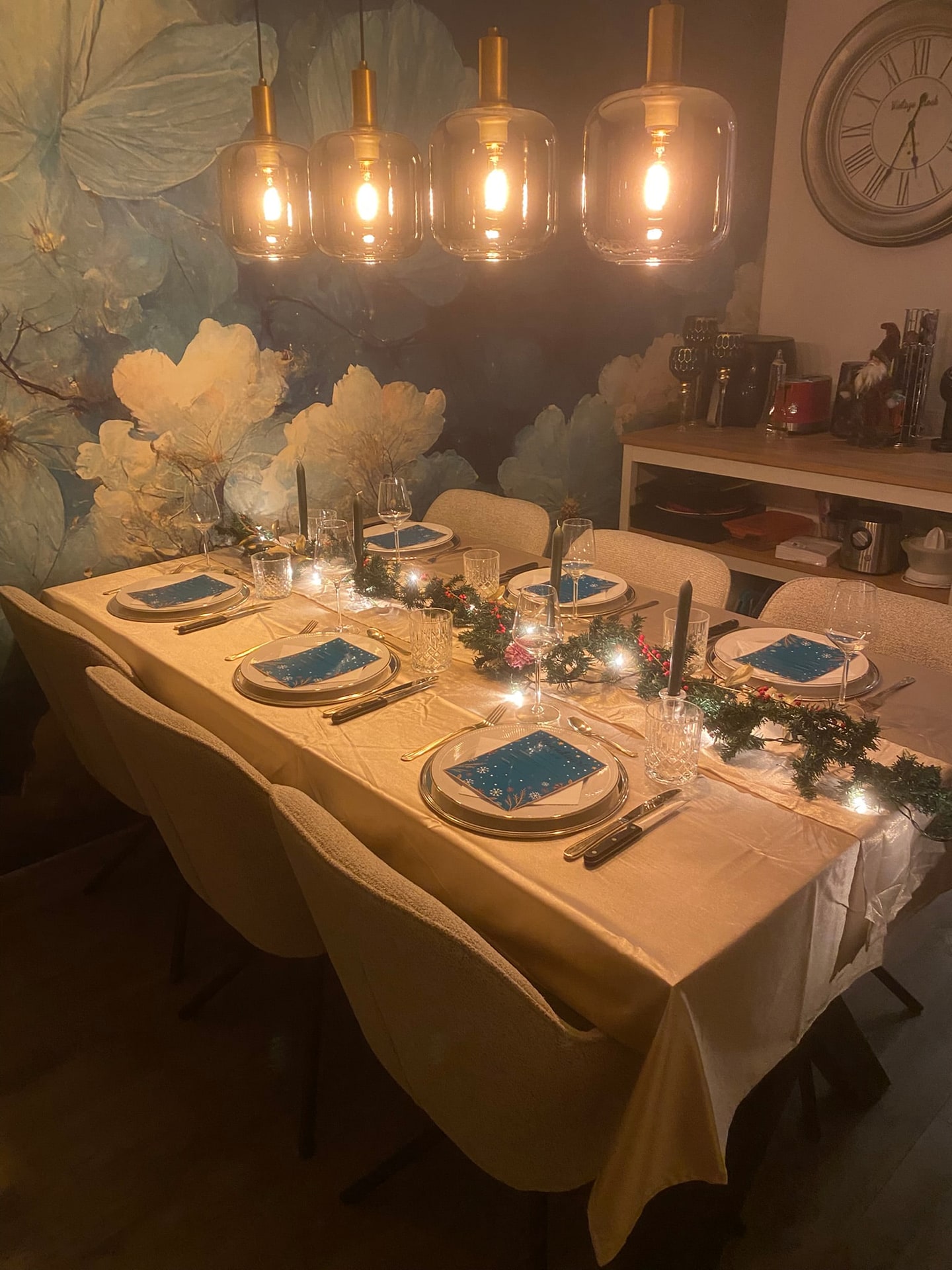 De gedekte kersttafel met kaarsen en hanglampen erboven