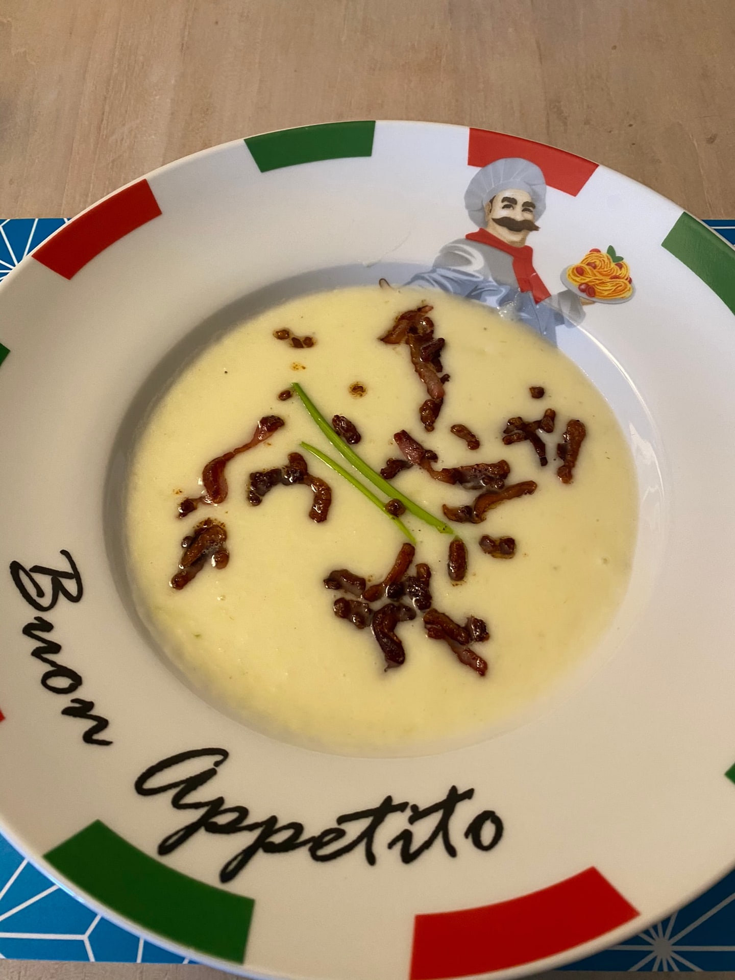 Een gele soep met een sliert donkere saus erdoorheen