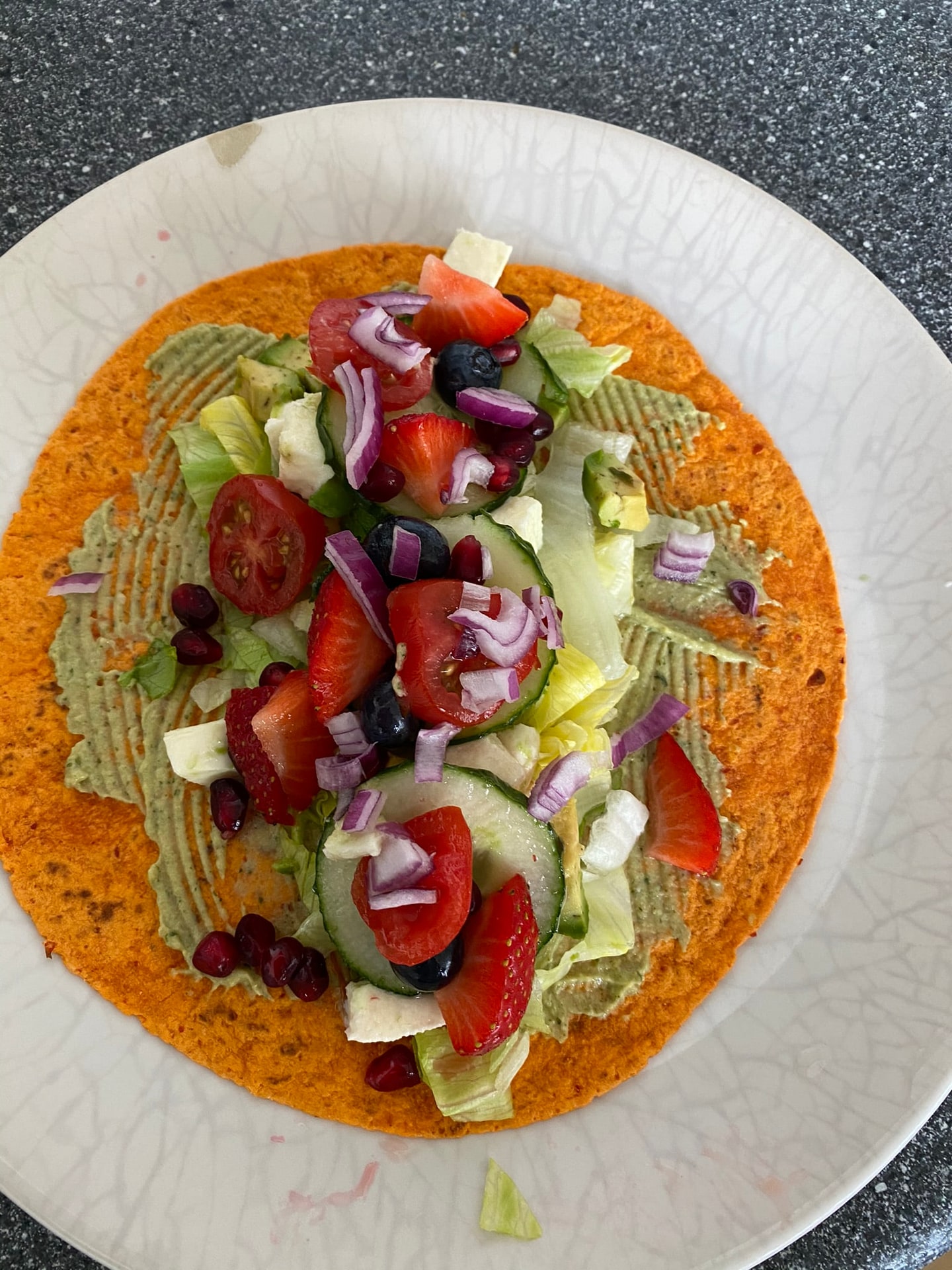 Een oranje wrap met sla, tomaat en rode ui