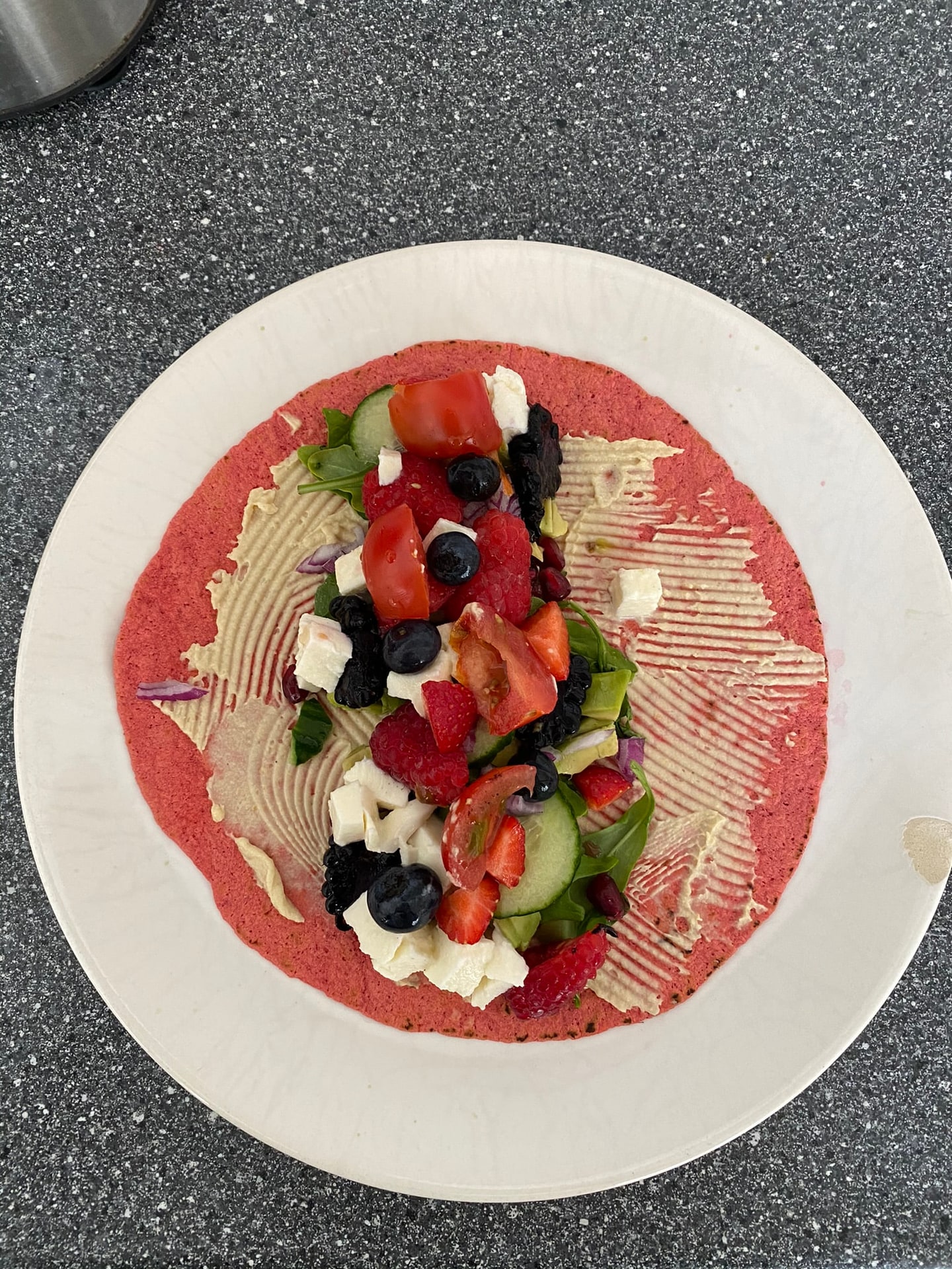 Een platbrood met tomaat, olijven en verkruimelde feta