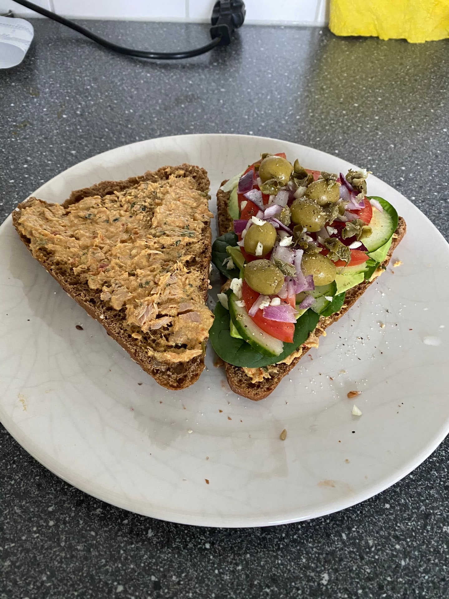 Twee sneden brood met avocado, olijf en komkommer