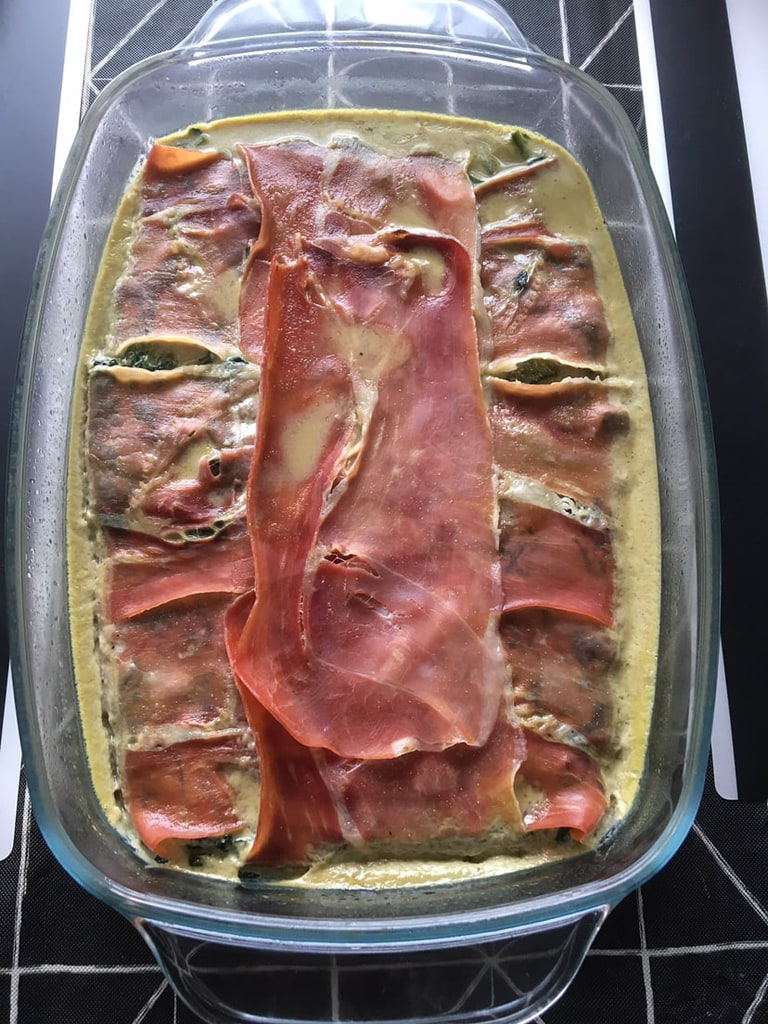 Een ovenschaal met ham over een groene vulling