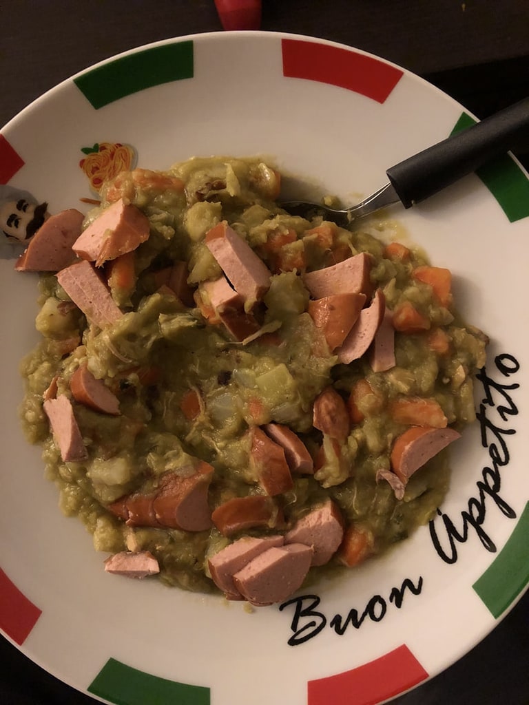Een bord met stoofpotje, worst en groenten