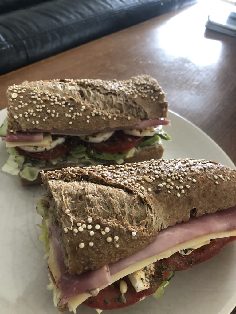 Een broodje met ham, kaas en sla, doorgesneden