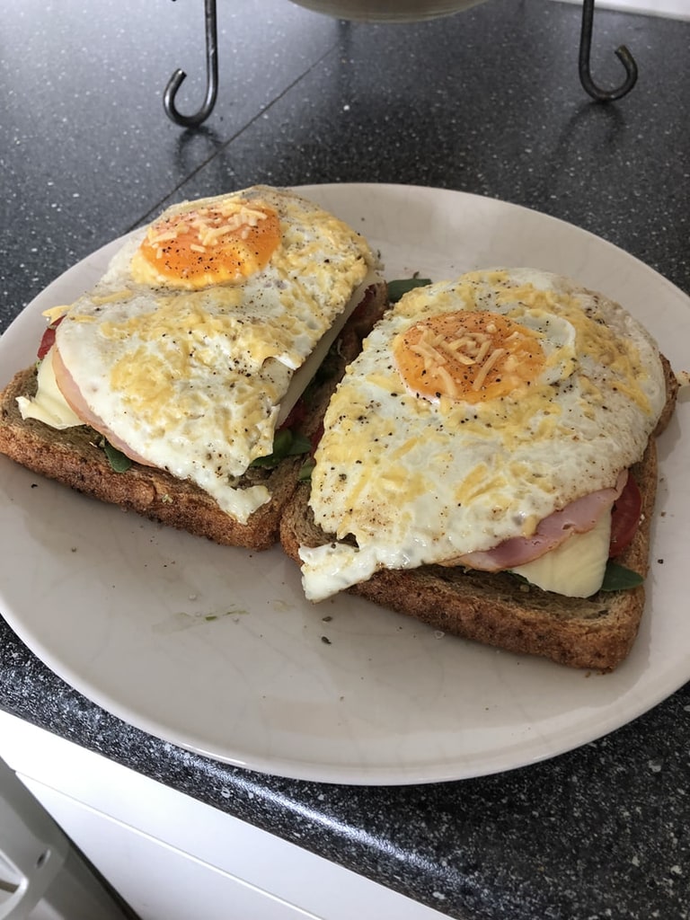 Twee sneden brood met ham en een spiegelei erop