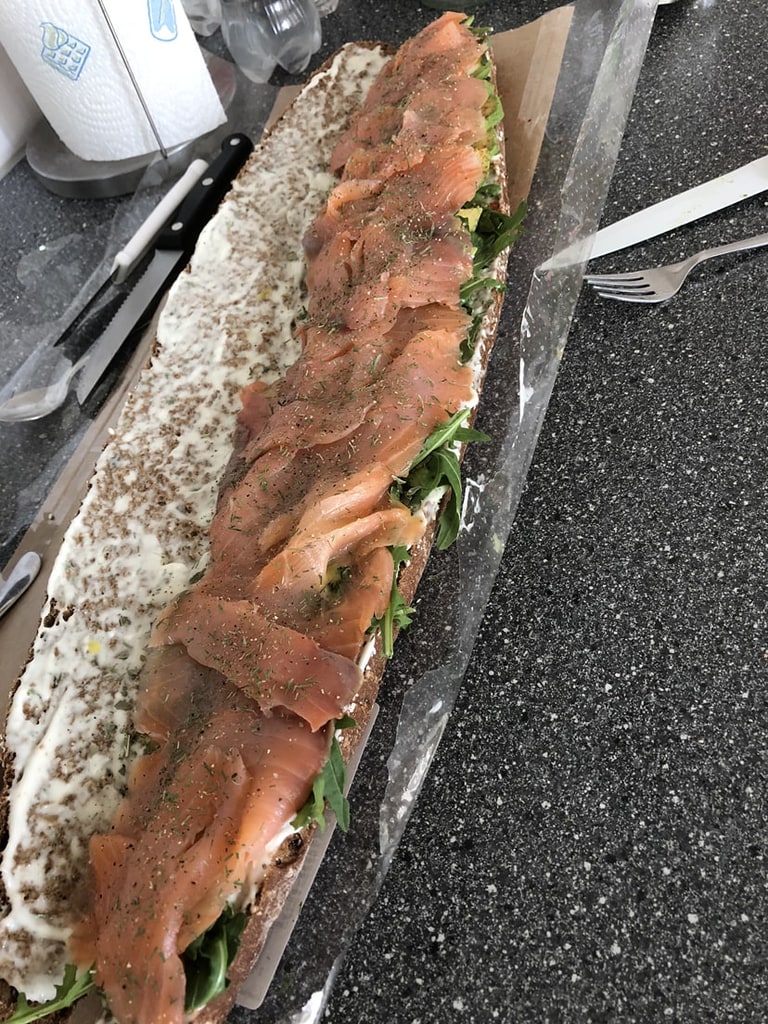 Een lang stokbrood belegd met gerookte zalm