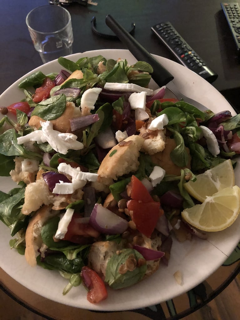 Een salade met sperziebonen, tomaat, ui en een partje citroen