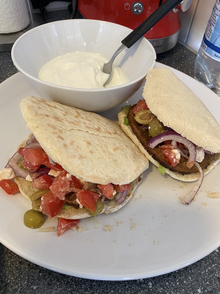 Twee pitabroodjes met vulling, met een kom yoghurt ernaast