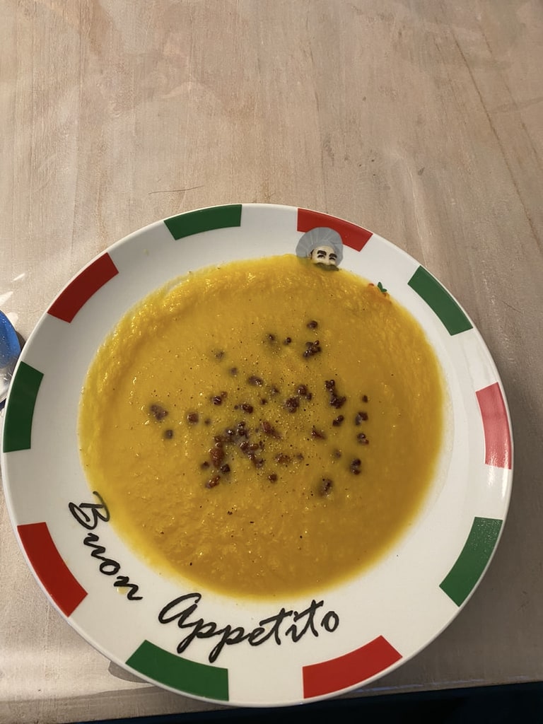 Een oranje soep met zwarte zaadjes erover