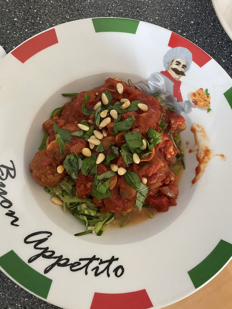 Een bord met tomatensaus, pijnboompitten en kruiden