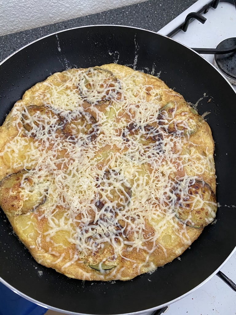 Een omelet met geraspte kaas in de koekenpan