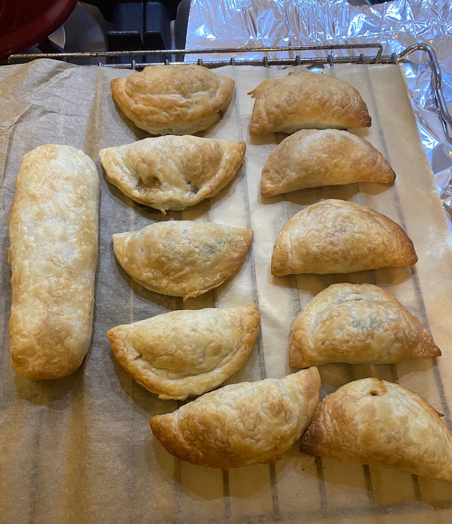 Een bakplaat met gebakken bladerdeeghapjes en een lange rol