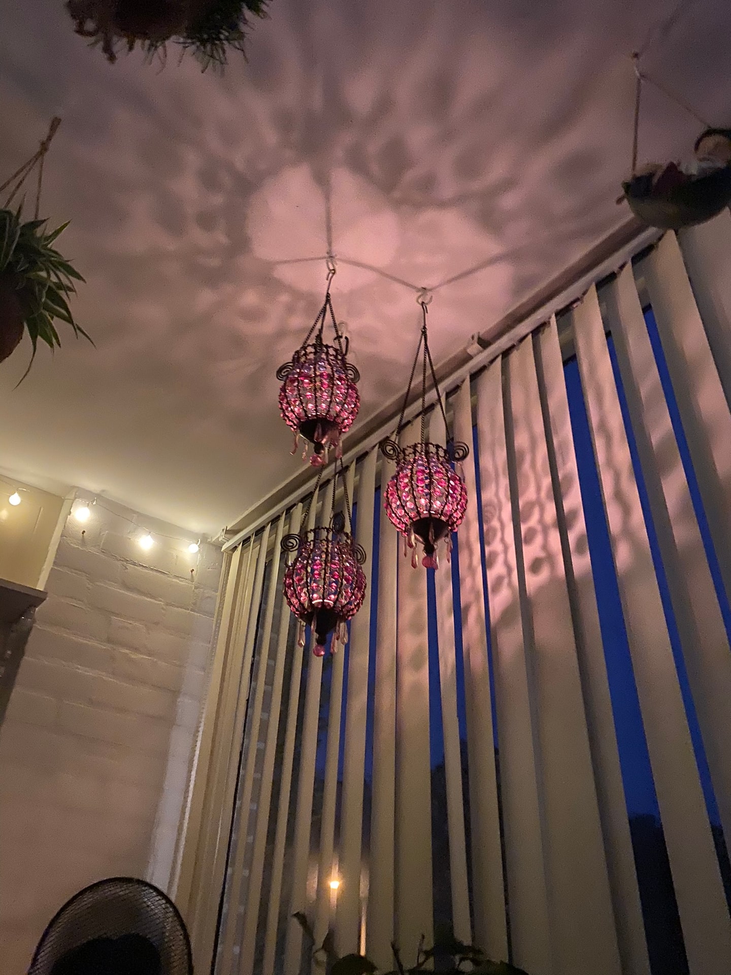 Drie sierlijke roze glazen hanglampen in de avond, met hun lichtpatroon over het plafond